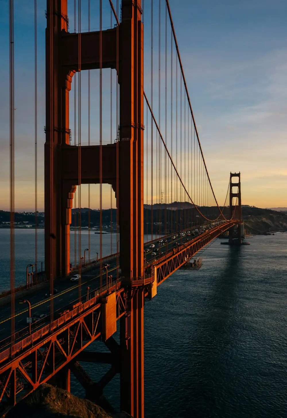 The Golden Gate Bridge at sunset, seen along the deck from the northern tower.